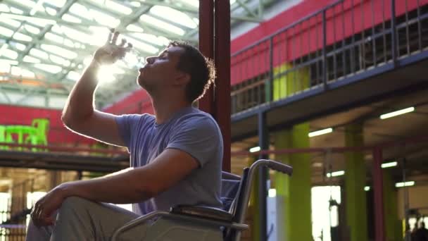 Portret mężczyzny niepełnosprawnych w wodzie do picia dla wózków inwalidzkich, po treningu w siłowni. Z bliska — Wideo stockowe