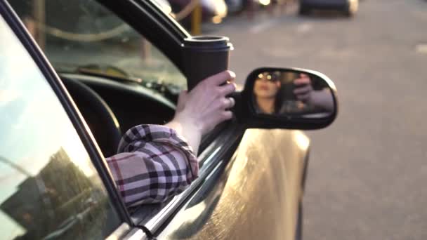 Młoda kobieta pije kawę i zgłasza kubek na ziemi z samochodu. Slow mo — Wideo stockowe