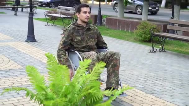 Um soldado deficiente numa cadeira de rodas em camuflagem — Vídeo de Stock