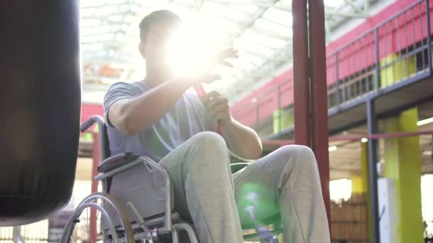 Homem retrato com uma deficiência em uma cadeira de rodas fitas de boxe ferida em suas mãos — Vídeo de Stock