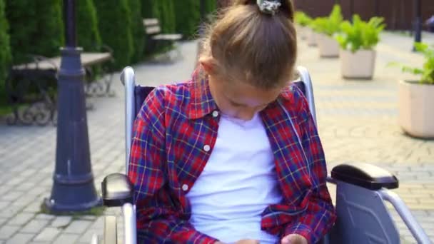 Портрет девочки-подростка с телефоном в руке в инвалидном кресле — стоковое видео