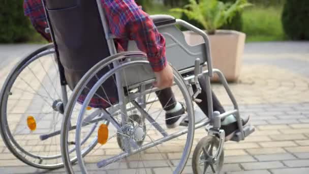 Close up de uma pessoa com deficiência que usa uma cadeira de rodas — Vídeo de Stock