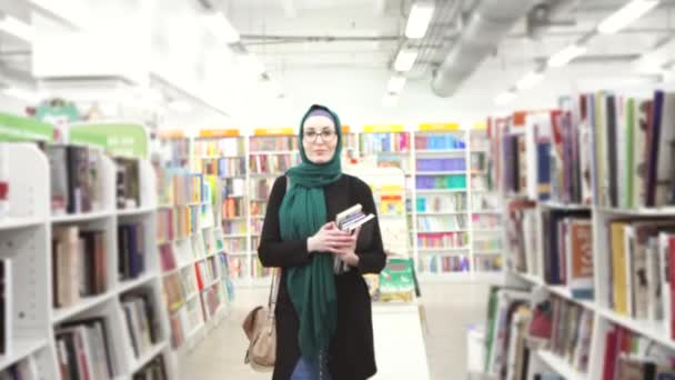 Meisje in hijab met boeken in handen in bibliotheek — Stockvideo