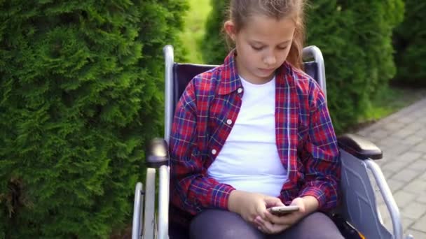 Handicap meisje in een rolstoel met behulp van de telefoon — Stockvideo