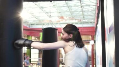 Boksör kadın kum torbasına spor salonunda bir egzersiz programı yapıyor. Yavaş mo kapatın