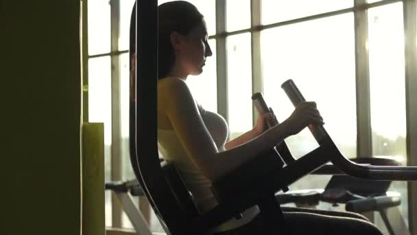 Hermosa mujer joven bombea la prensa en un elegante gimnasio de cerca — Vídeo de stock