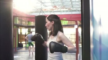 Boksör kadın kum torbasına spor salonunda bir egzersiz programı yapıyor. Yakın çekim