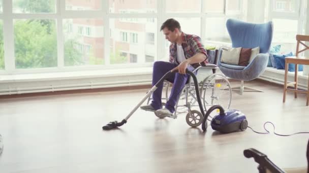 Man in een rolstoel te reinigen met een stofzuiger — Stockvideo