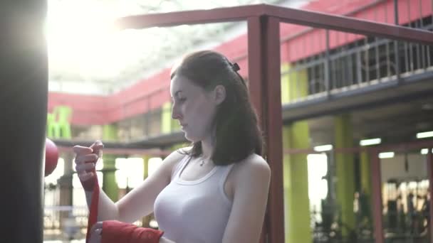 Mujer envuelve sus manos con una cinta de boxeo en un gimnasio de moda al atardecer. — Vídeo de stock