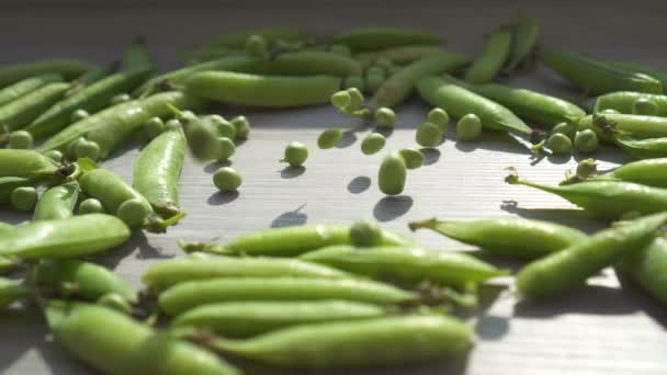 Guisantes verdes frescos cayendo sobre la mesa de cerca — Vídeos de Stock