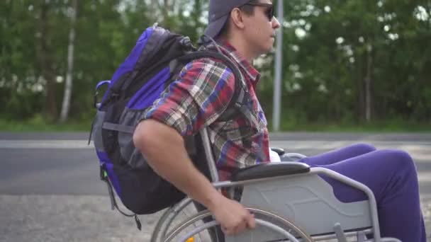 Portret van een man die reizen uitgeschakeld in een rolstoel met een rugzak — Stockvideo