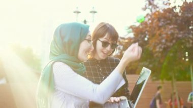 Tesettür ve dizüstü bilgisayar ile onun arkadaşı Müslüman öğrenci sevinirler, sunflare. Yavaş mo
