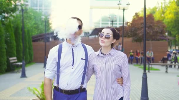 Eleganta mannen med e cigarett och flicka promenader i parken, sunflare. Långsamma mo — Stockvideo