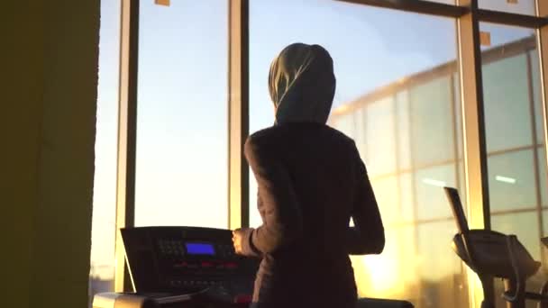 Mladý sportovní muslimská dívka v hidžábu na běžeckém pásu. Sunflare — Stock video