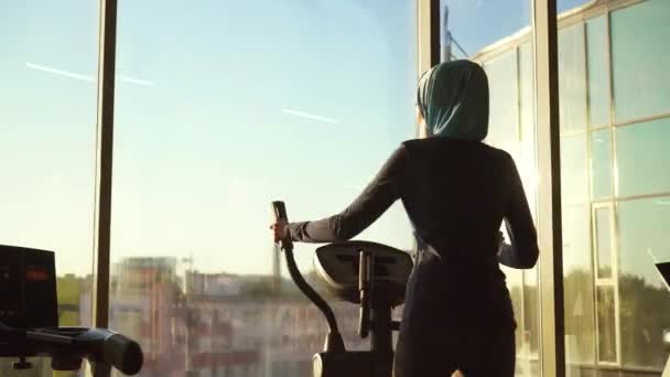 Young sporty muslim woman in hijab doing sports on the simulator — Stock Video