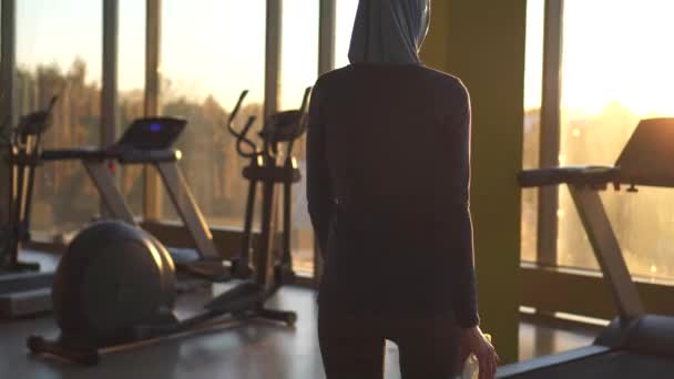 Jovem menina muçulmana desportiva no hijab vai para o simulador e começa a praticar esportes — Vídeo de Stock