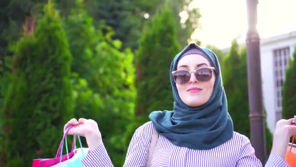 Retrato de una joven musulmana con estilo con bolsas en las manos después de ir de compras — Vídeo de stock
