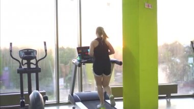 Spor salonunda bir koşu bandı üzerinde çalışan genç sporcu kadın
