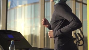 Bir koşu bandı üzerinde çalışan bir hijab genç sportif Müslüman kız kapatın. Yavaş mo