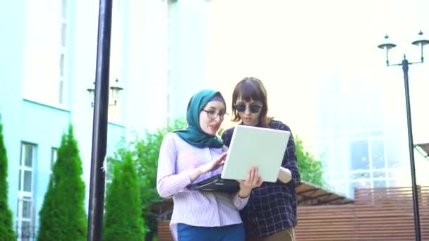 Muslim girl in hijab and her friend are happy looking at laptop — Stock Video