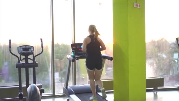 Young athlete woman running on a treadmill in the gym — Stock Video