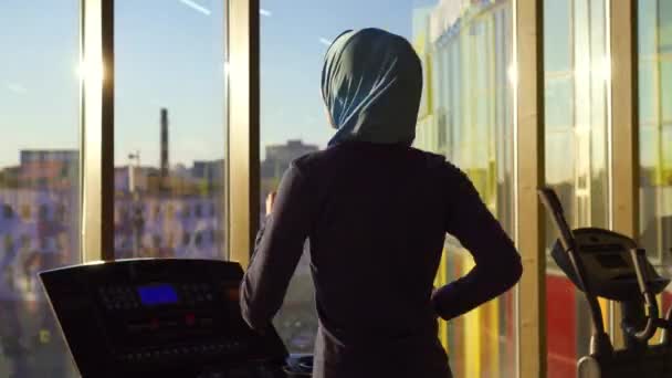 Närbild av ung muslimsk tjej i hijab gör sport på löpbandet — Stockvideo