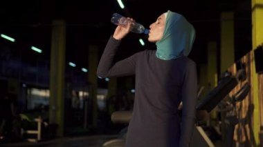 Genç sportif Müslüman kız hijab içme suyu çalışmadan sonra şişe