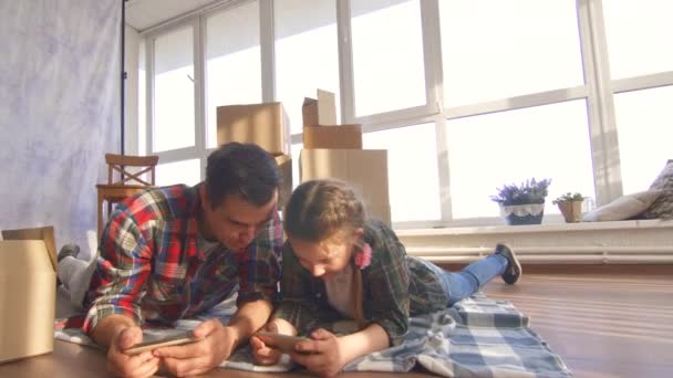 Vater und Tochter liegen auf dem Boden und benutzen ein Smartphone — Stockvideo