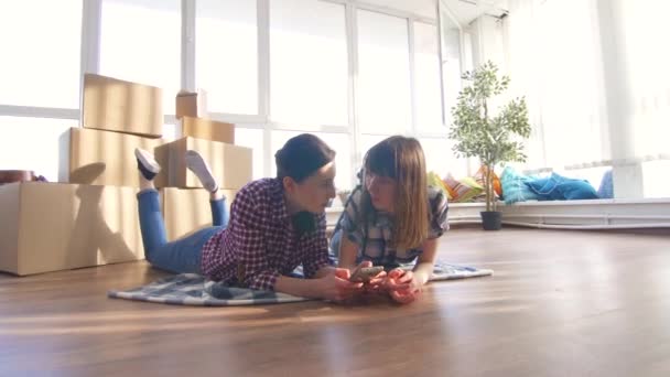 Gleichgeschlechtliches Paar liegt auf dem Boden und genießt das Smartphone — Stockvideo