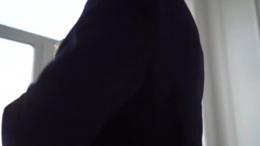 Kravatını pencerenin önünde bir ceketli adamı düzeltiyor