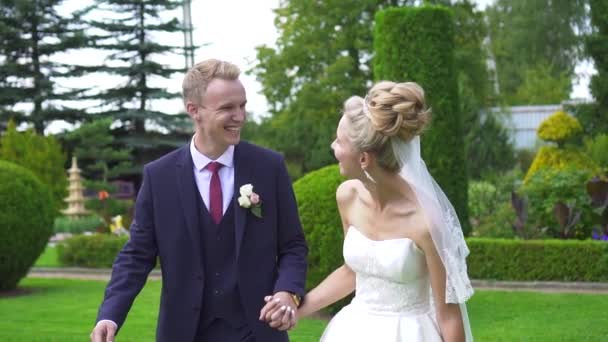 Retrato de la hermosa novia y el novio sonriendo en el jardín, caminar — Vídeo de stock