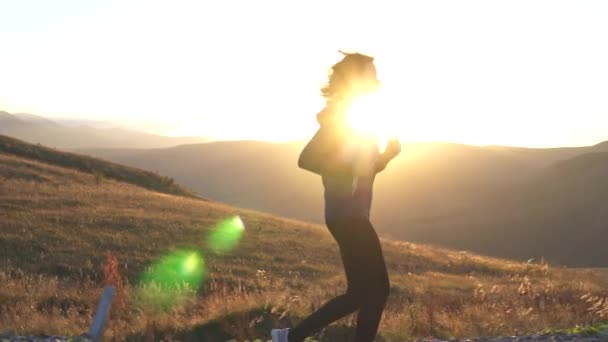 Chica corriendo en la carretera en las montañas al atardecer, rayos de sol — Vídeos de Stock