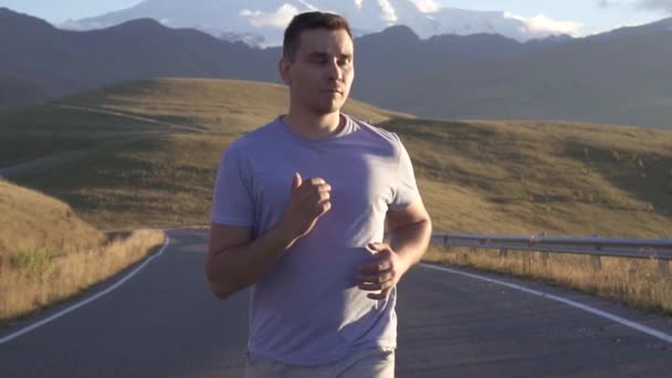 Retrato homem corre na estrada para as montanhas, slow mo — Vídeo de Stock