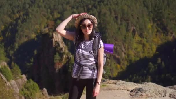Porträt eines Touristenmädchens mit Rucksack auf dem Rücken in den Bergen — Stockvideo