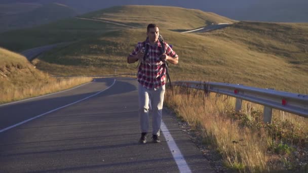 Uomo turista con uno zaino dietro va sulla strada per le montagne, lento mo — Video Stock