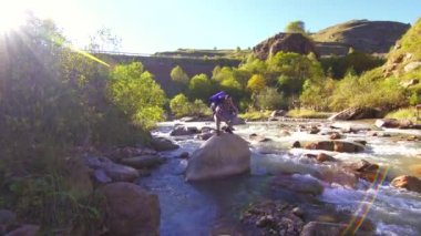 Bir dağ nehir üzerinde sırt çantası ile adam uzun yürüyüşe çıkan kimse sevinir