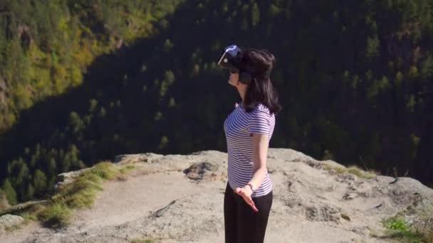 Girl wearing virtual reality glasses on a sunny day in the wild in the mountains — Stock Video