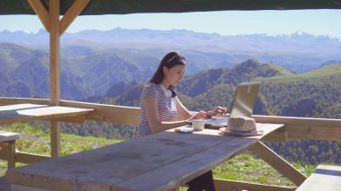 Kız serbest meslek blogger dağlarda doğada güzel bir yerde çalışıyor
