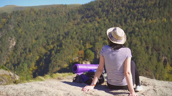 turist kızla Dağlarda oturan şapkalı bir sırt çantası