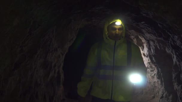 Ritratto uomo ricercatore volontario con una torcia in mano sta cercando nella grotta — Video Stock