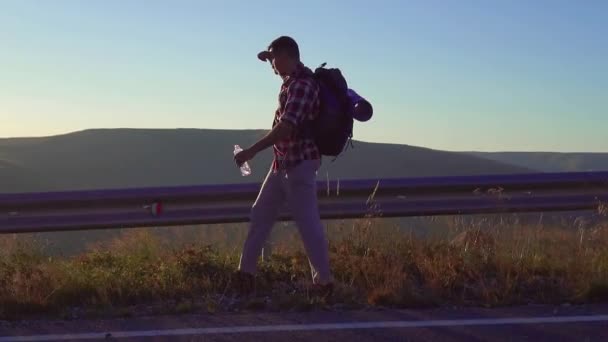 男は彼の後ろにバックパックの旅は道路上 — ストック動画