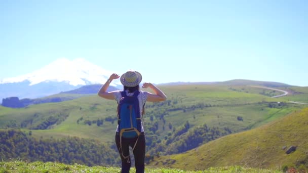 Girl tourist with backpack gesturing success on the mountain, winner concept — Stock Video