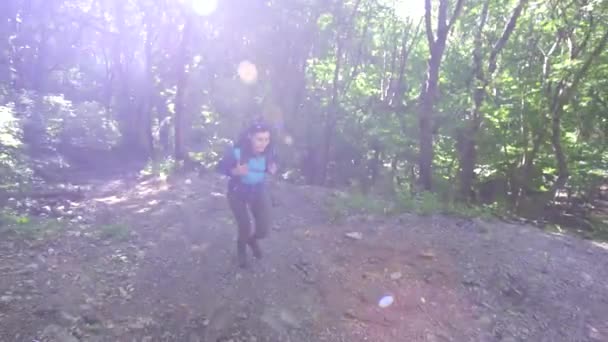 Girl tourist with a backpack up the trail in the woods,sun ray — Stock Video