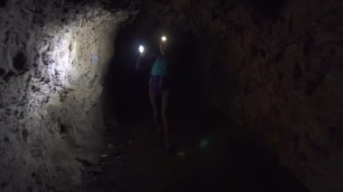 Kız turist sırt çantası onun alnına ve onun elinde bir fenerle ile karanlık bir mağarada ve keşfetmek olduğunu