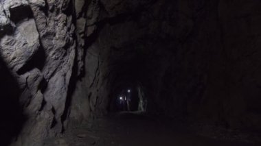 Derin karanlık bir mağarada bir el feneri ile kız ve erkek turistler geçmesi