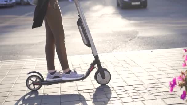 Wooman bir elektrikli scooter güneşli bir şehir sürmek. — Stok video