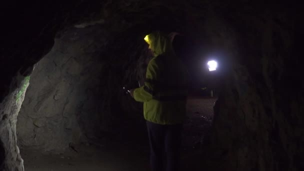 Hombre voluntario con una linterna está buscando a un hombre en una cueva oscura, lento mo — Vídeos de Stock