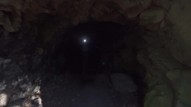 Girl tourist with a backpack runs out of the dark cave and enjoys raising his hands up — Stockvideo