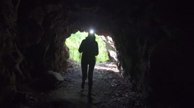 Karanlık bir mağaraya kız gezgin alnına bir el feneri ile bir sırt çantası ile gelir