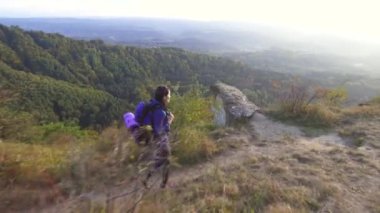 Yalnız kadın turist sırt çantası ile bir dağ yolda seyahat ve etrafına bakıyor